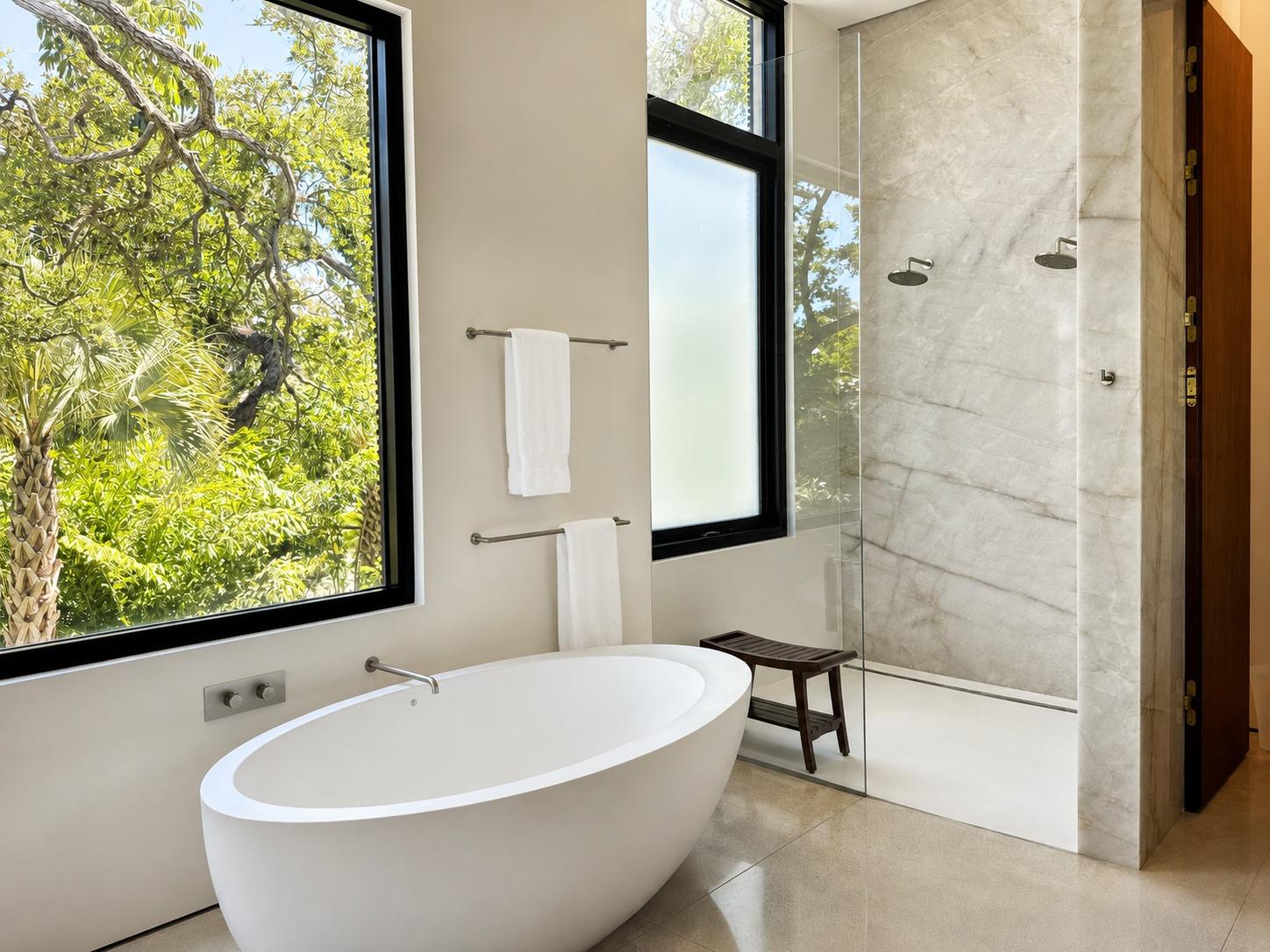 Spotless bathroom with a freestanding soaking tub, glass-enclosed marble shower, and fresh white towels