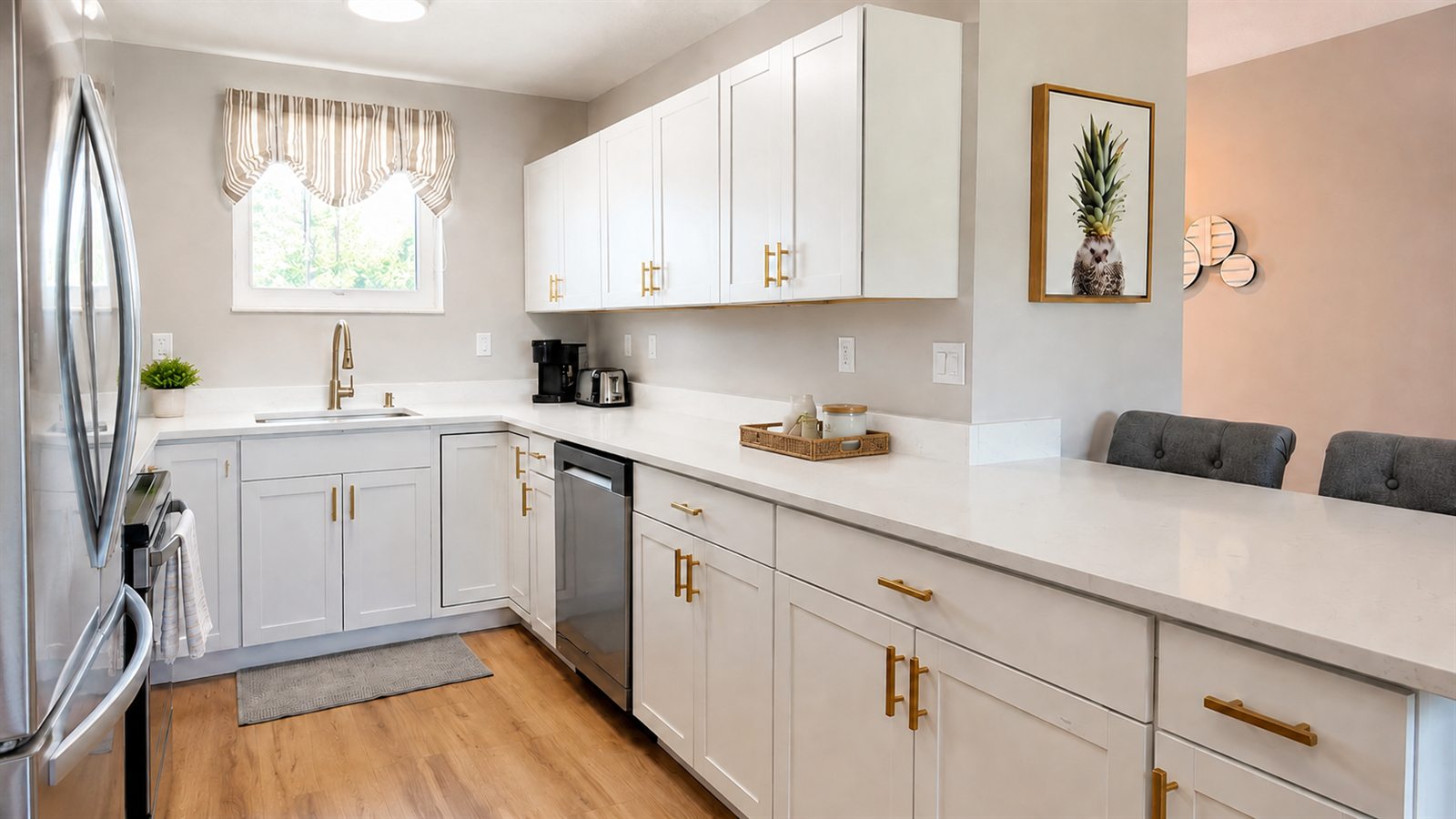 Bright white kitchen with clean countertops, polished appliances, and gleaming floors