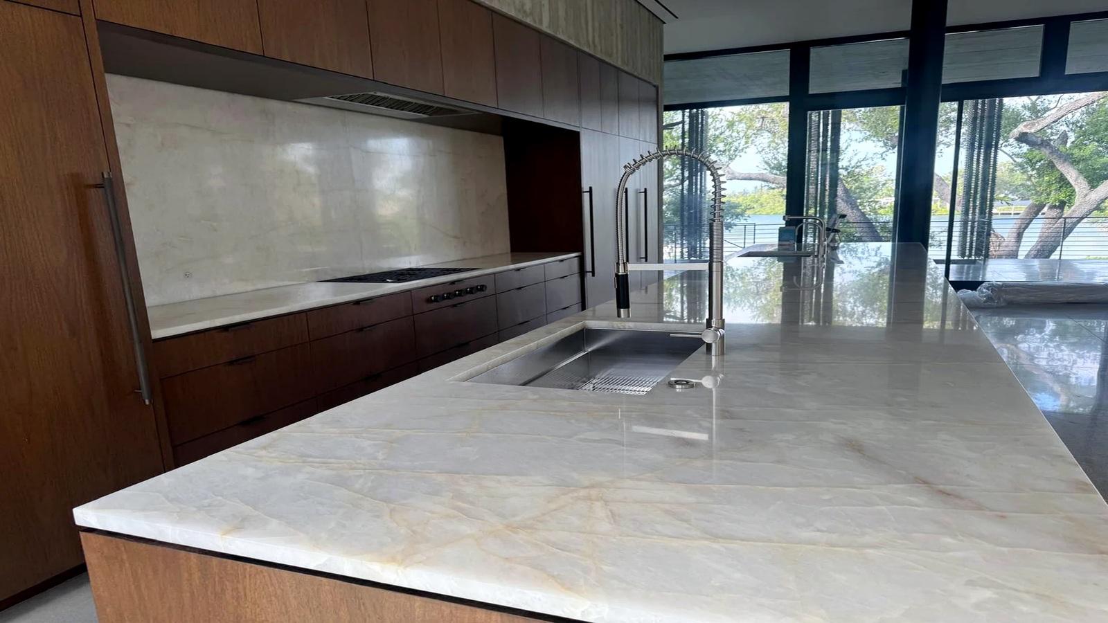 Spotless marble kitchen island and stainless sink in an empty home, ready for handover